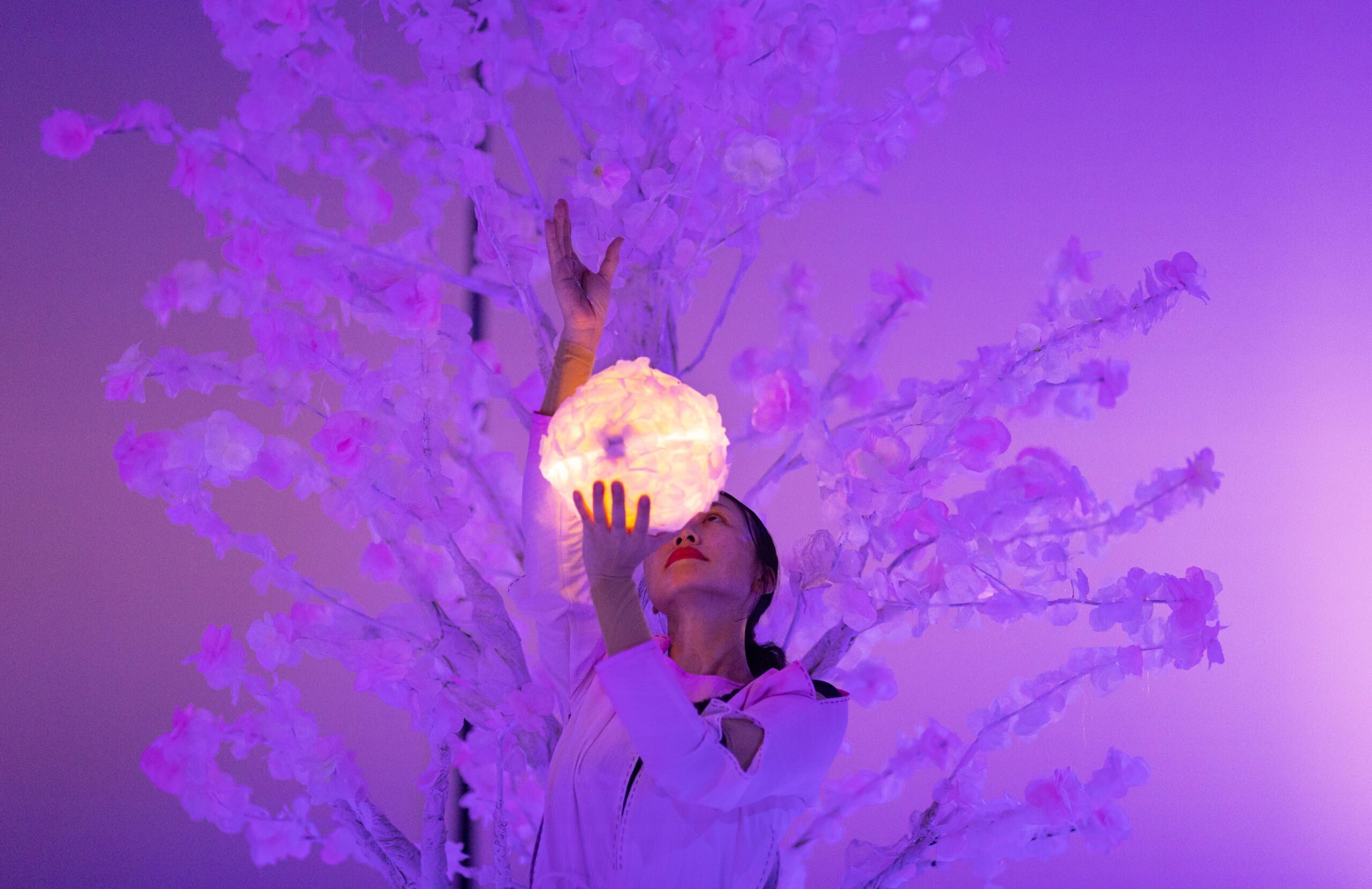 Płatki i baśnie, zdjęcie ze spektaklu Panta Rei Danseteater. Tancerka stoi na tle białego drzewa, w ręku trzyma puszystą świecącą białą kulę.