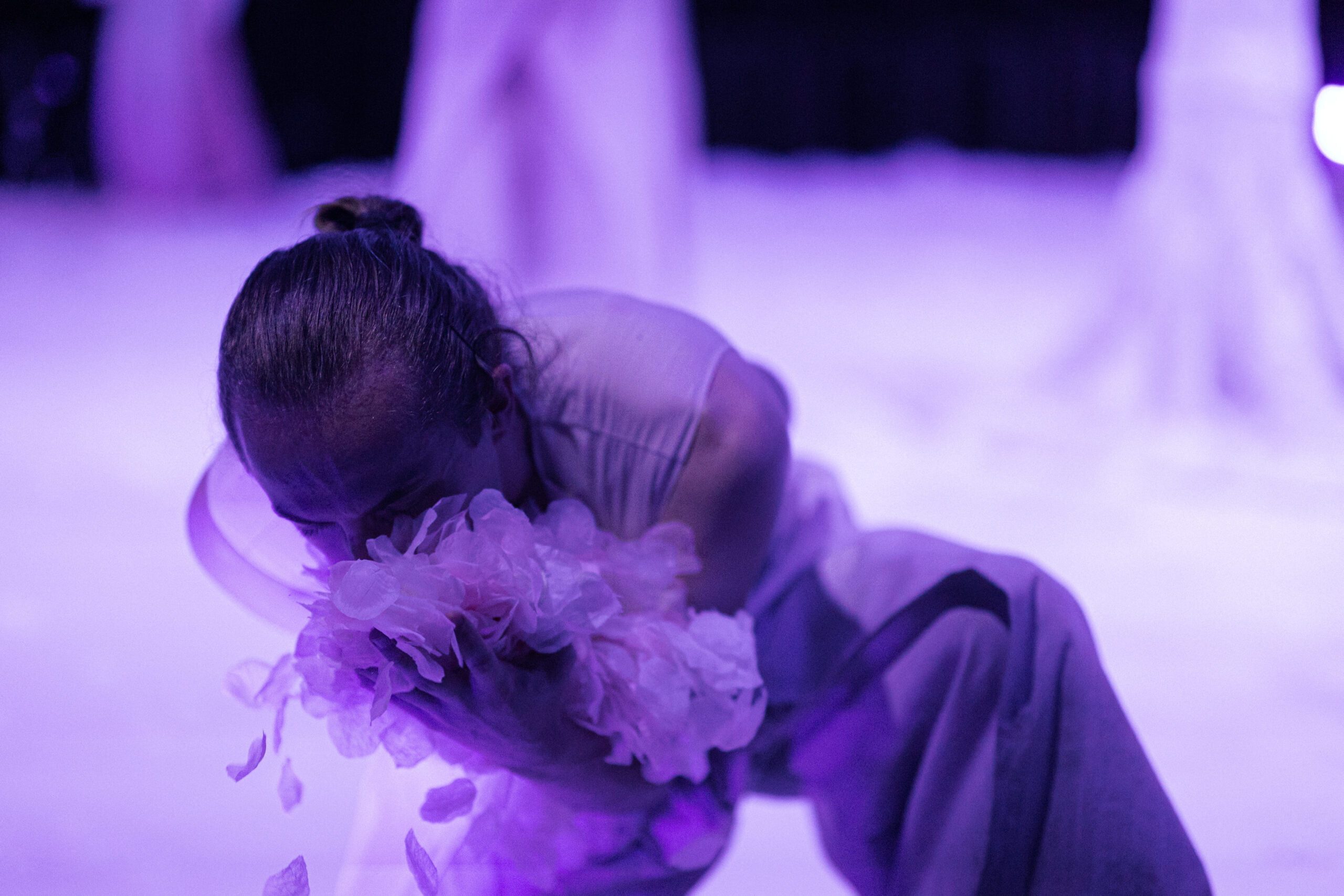 Płatki i baśnie, zdjęcie ze spektaklu Panta Rei Danseteater, tancerz pochylony do przodu chowa twarz w imitacji płatków kwiatów