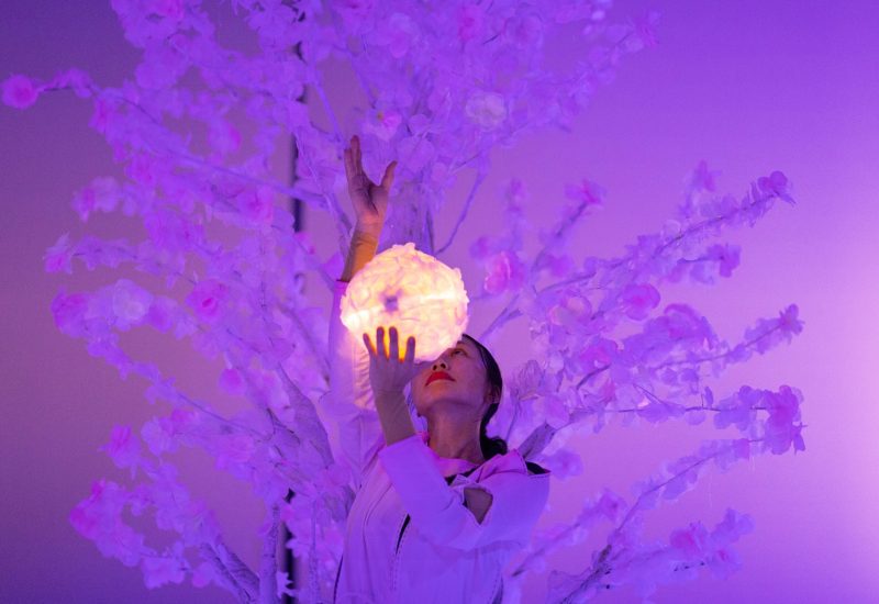Płatki i baśnie, zdjęcie ze spektaklu Panta Rei Danseteater. Tancerka stoi na tle białego drzewa, w ręku trzyma puszystą świecącą białą kulę.